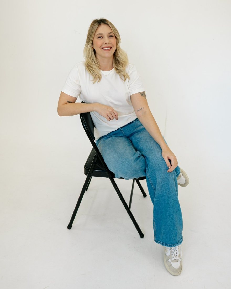 Suélen Meneghelli sentada em uma cadeira, sorrindo